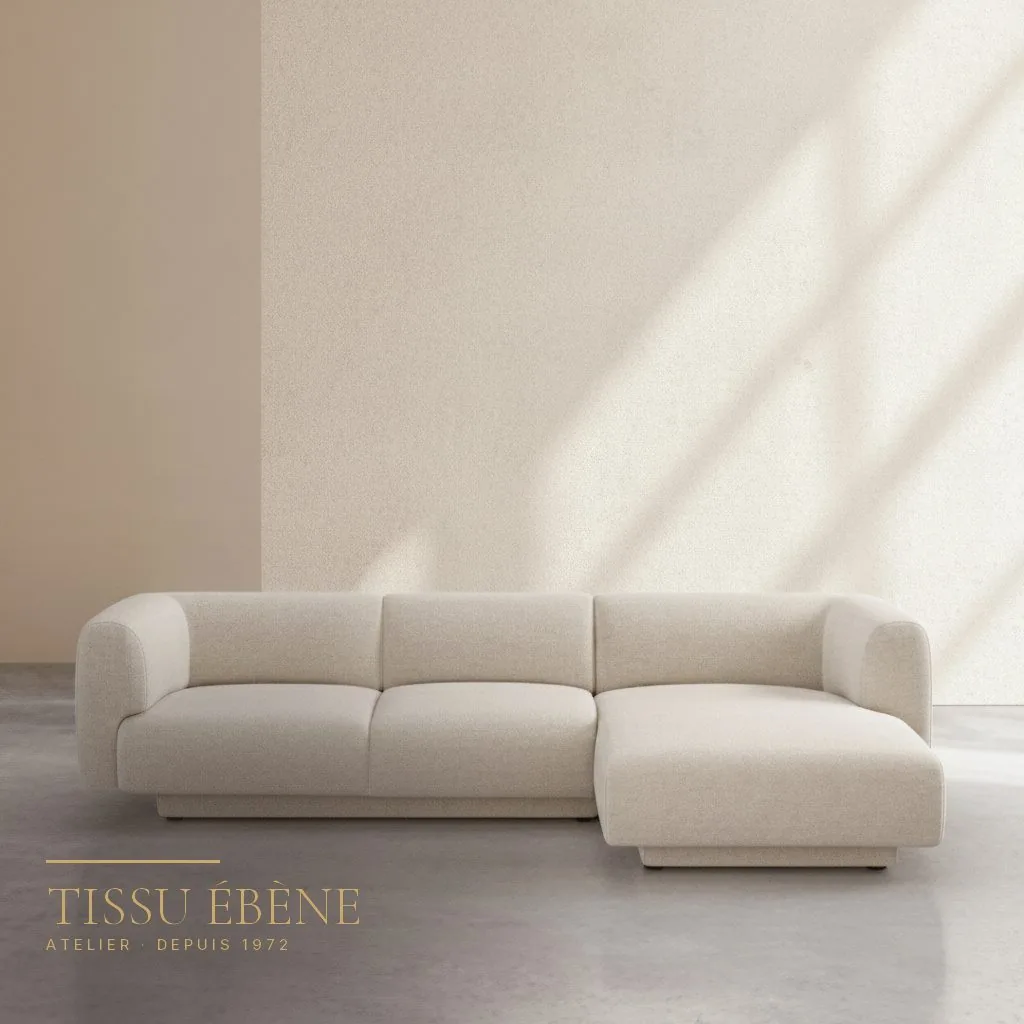 Canapé d’angle en tissu bouclé crème aux formes arrondies devant un mur clair