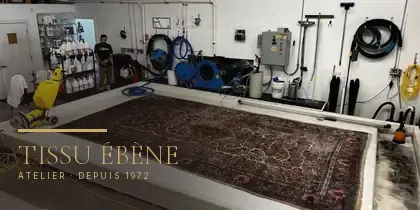 Grand tapis d'Orient posé à plat sur la table de lavage, avant le dépoussiérage