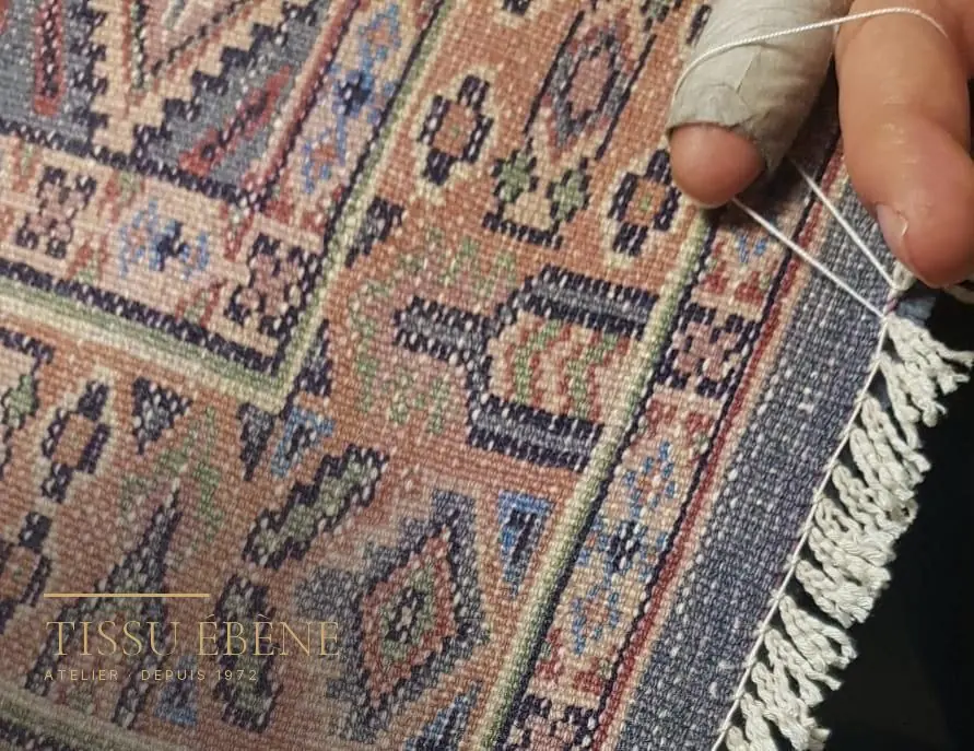 Examen du revers d'un tapis noué main, où se lisent la densité des nœuds et les reprises anciennes