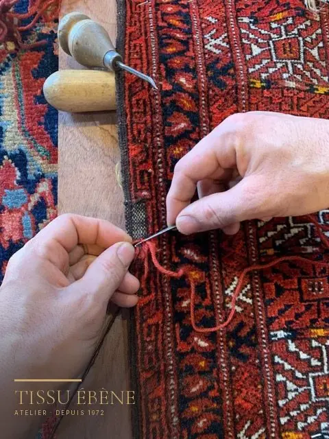 Lisière de tapis reprise à l'aiguille avec une laine teinte au ton de la pièce