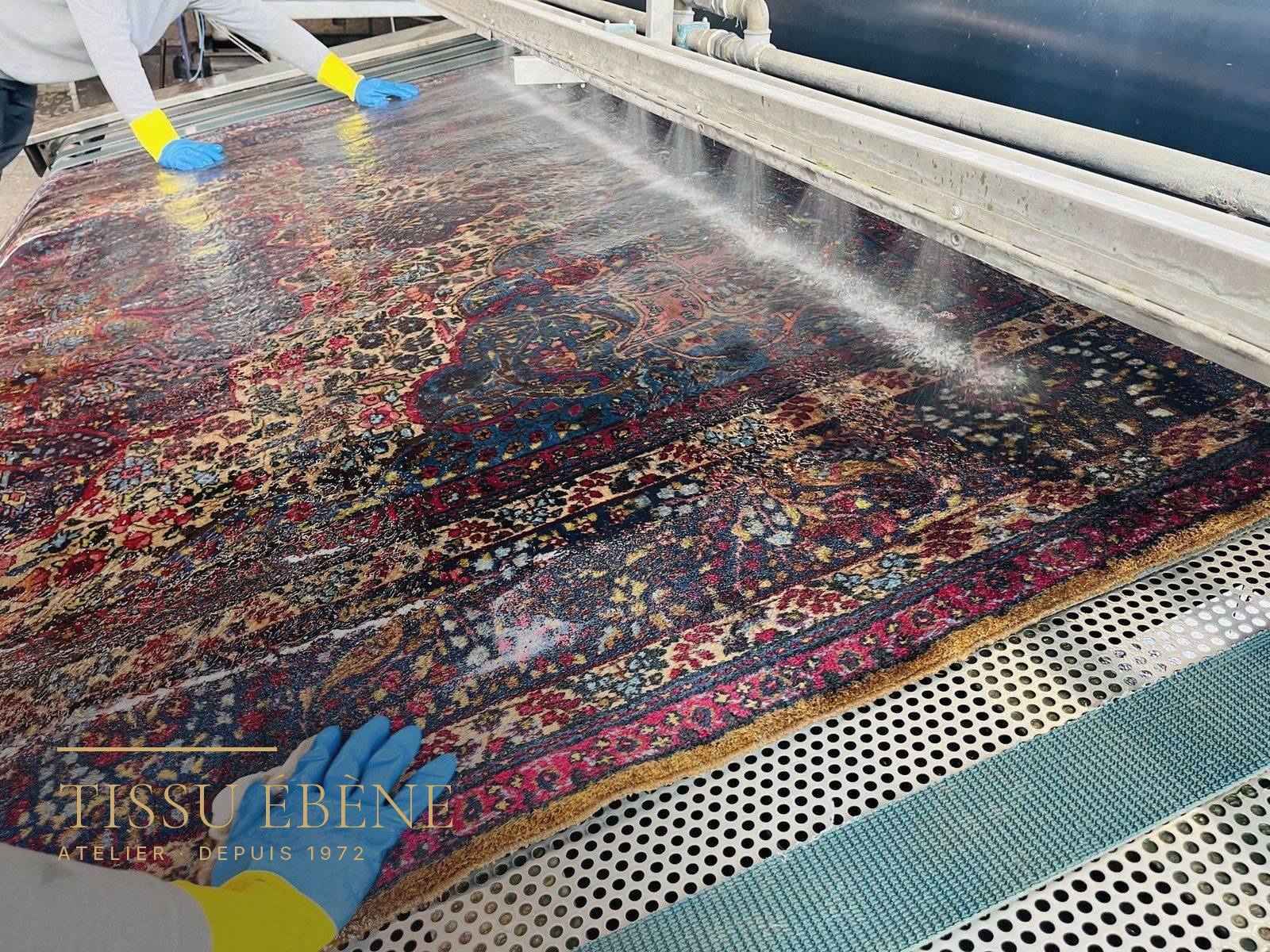 Tapis persan rincé à l'eau claire, à plat, sur la table de lavage de l'atelier