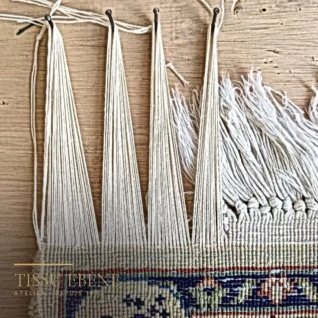 Réparation de franges de tapis : fils de chaîne repris un par un sur base saine, à l&rsquo;atelier